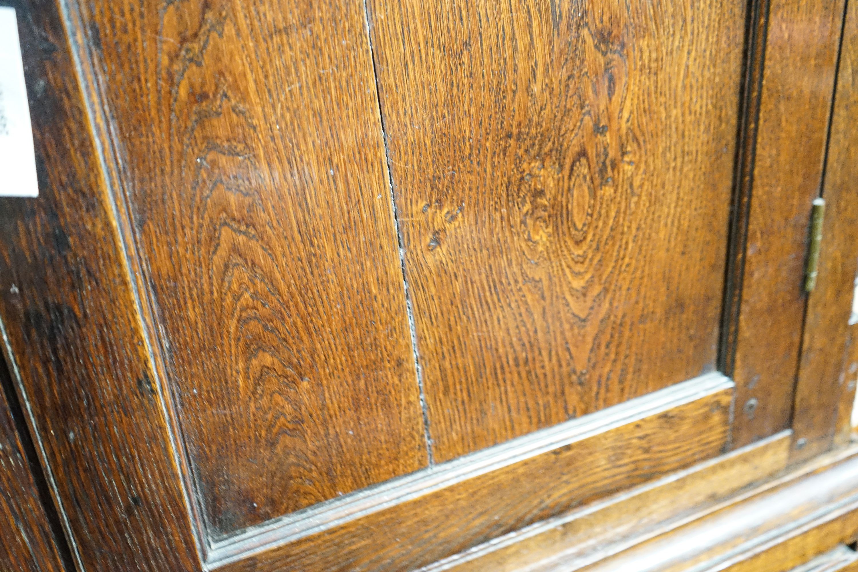 A George III oak press cupboard, with moulded cornice and two panelled doors over five drawers, width 122cm, depth 52cm, height 183cm